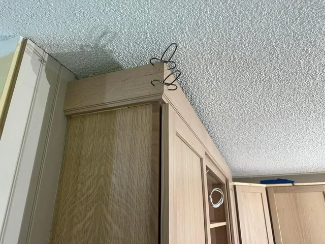 A kitchen with wooden cabinets and a ceiling with hooks on it.