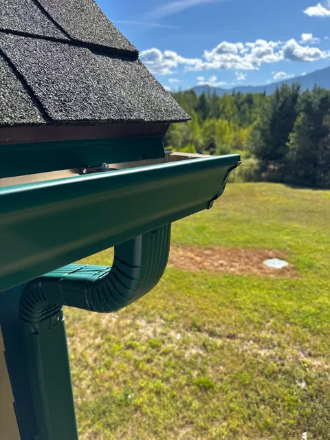 Forest green gutter installation with mountain views