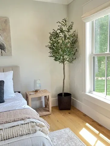 A guest bedroom with a olive tree decor and natural wood furniture.