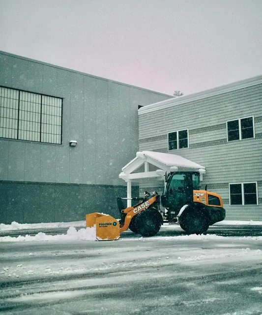 Snow removal equipment clearing a commercial property parking lot during winter in New Hampshire, operated by Perfect North Lawn Care.