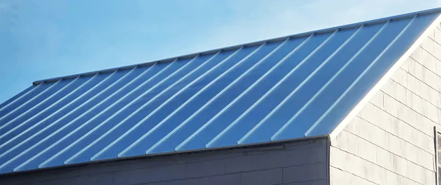 Seamless gutter replacement installed flush against a metal roof edge