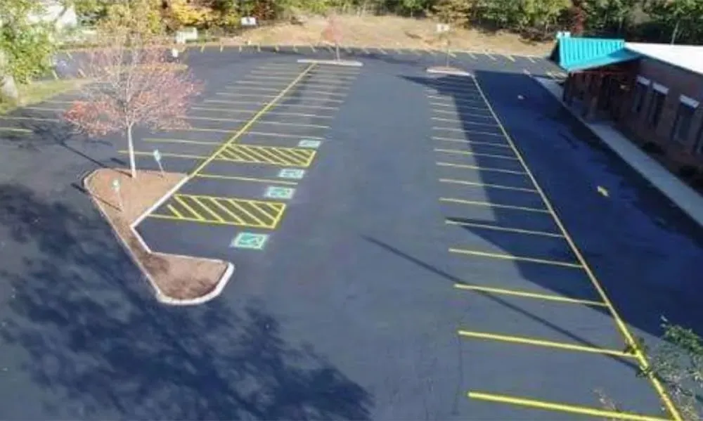 Asphalt parking lot with yellow lines, handicapped parking spots, and a building on the right.
