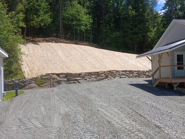 Stabilized slope with stone retaining wall and fresh gravel drive