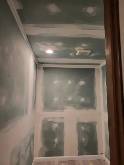 Unfinished drywall room with taped seams, ceiling light, and vent opening