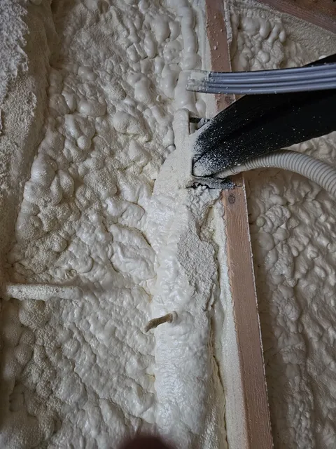 Mini-split lines sealed into closed-cell spray foam where they run down a stud wall