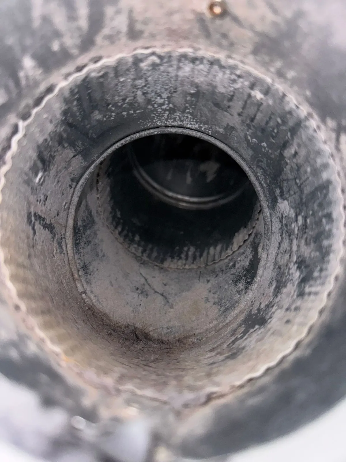 Interior of a dryer duct after cleaning, with bare metal walls and the full diameter restored.