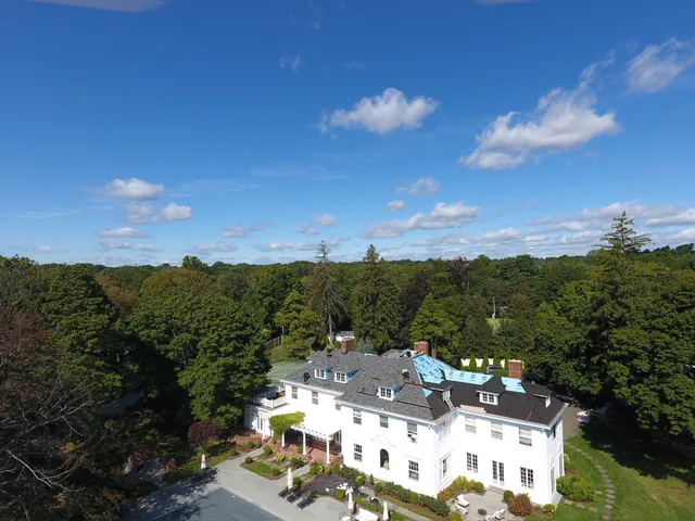 Drone view of roof replacement work across a large home's roofline