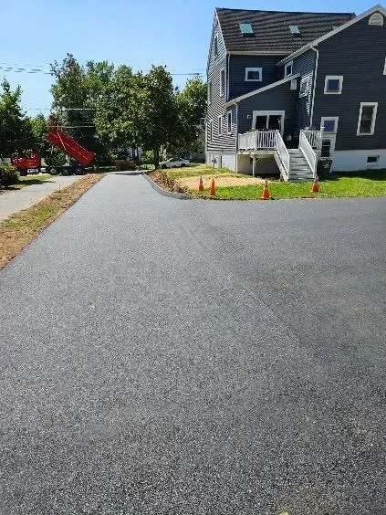 A curved paved path bordered by red mulch and greenery on a bright day.
