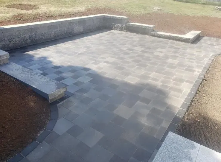 A patio with a stone wall and steps leading to it.