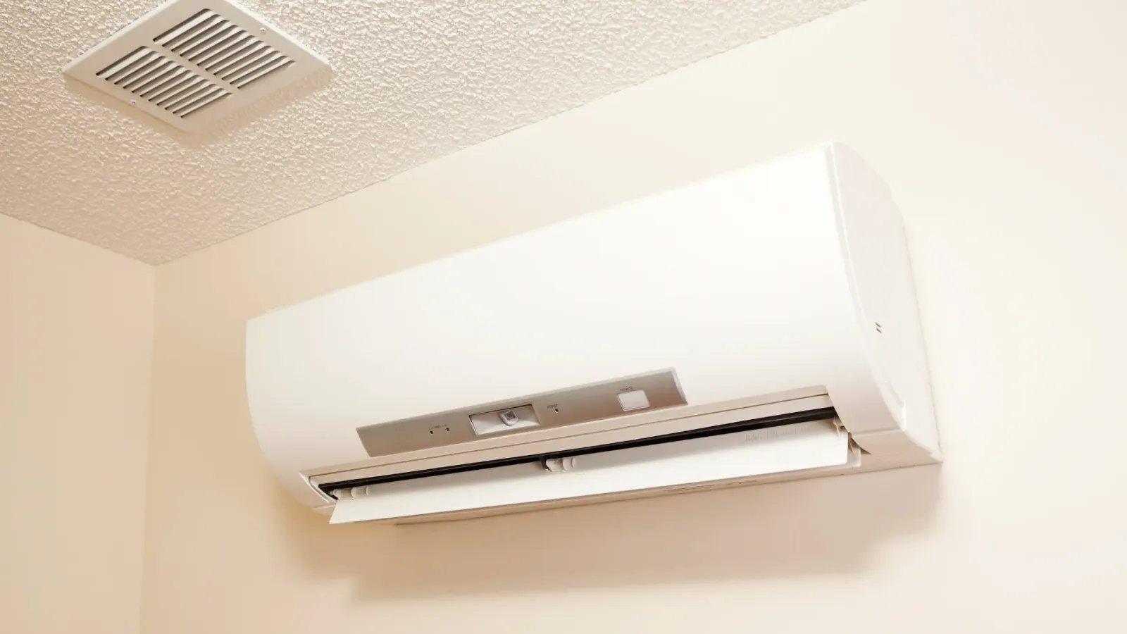 A white air conditioner is hanging from the ceiling in a room.