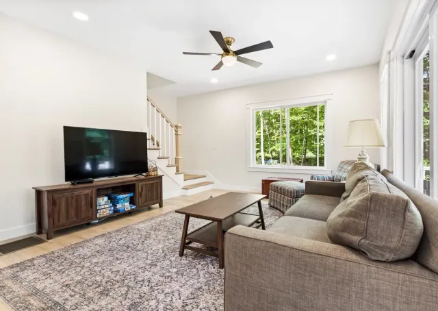 A living room with a couch, table, television, and ceiling fan.