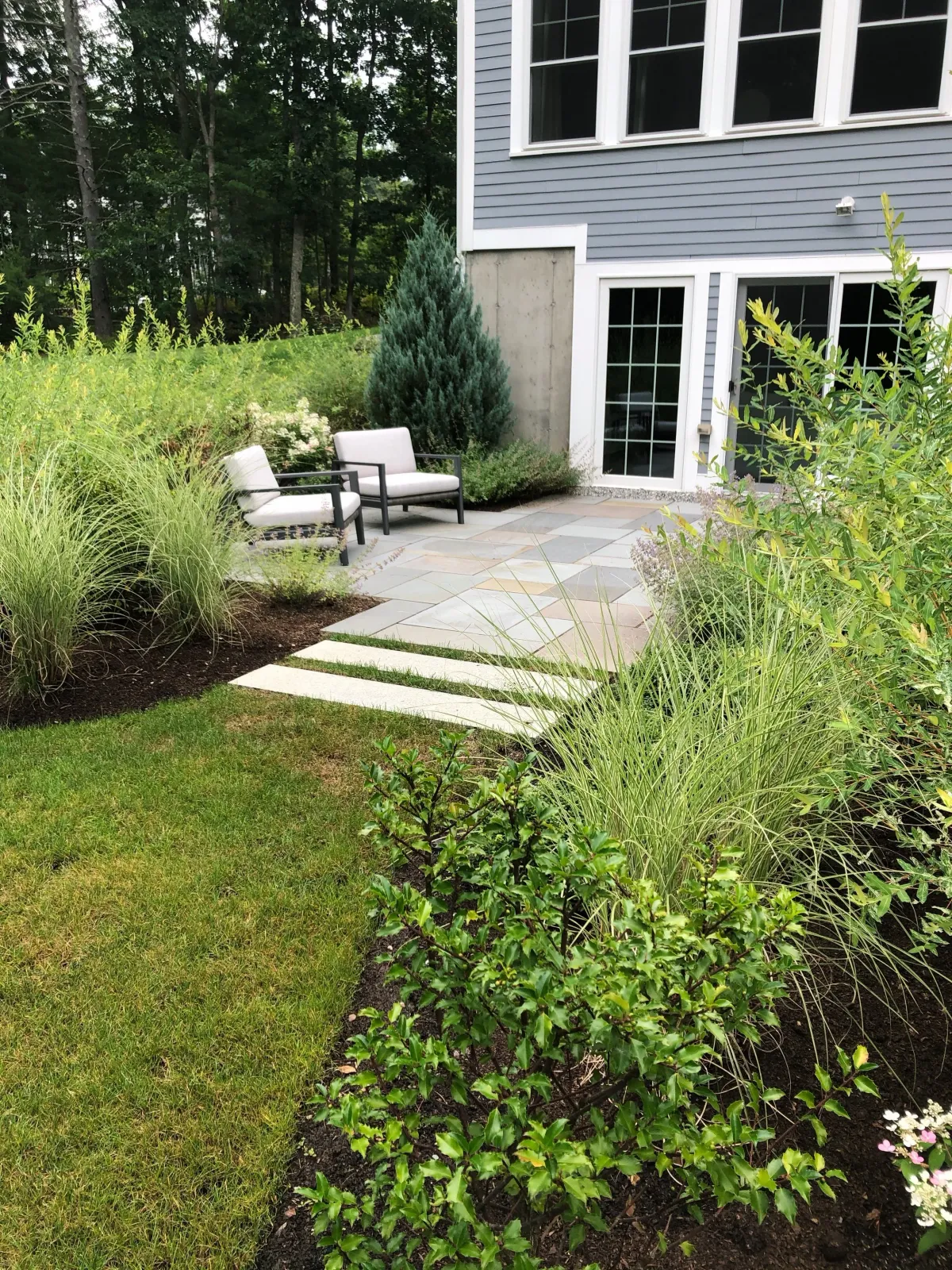 A walkout basement gets its own blue stone patio and landscape design to create additional outdoor entertainment space at this Boxford home.