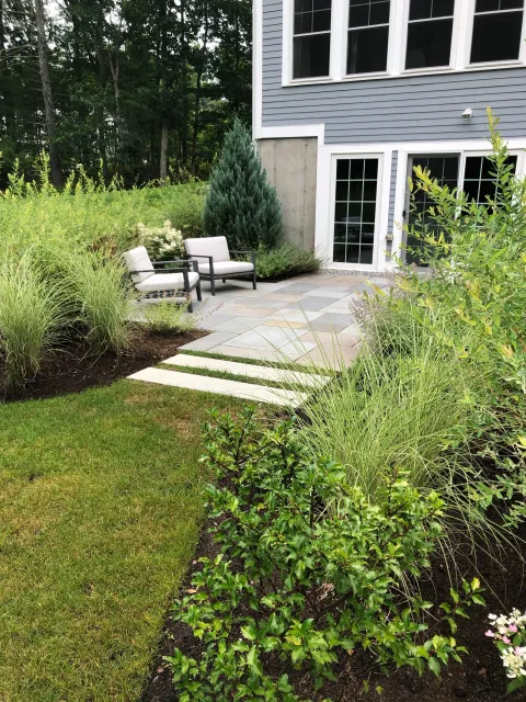 A walkout basement gets its own blue stone patio and landscape design to create additional outdoor entertainment space at this Boxford home.