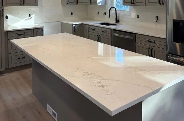 Modern kitchen with a large white island countertop and gray cabinets underneath.