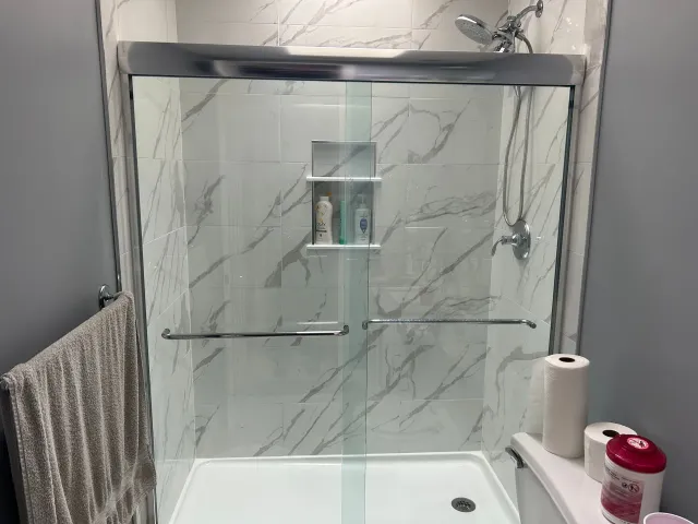 A bathroom with a sliding glass shower door and a toilet.