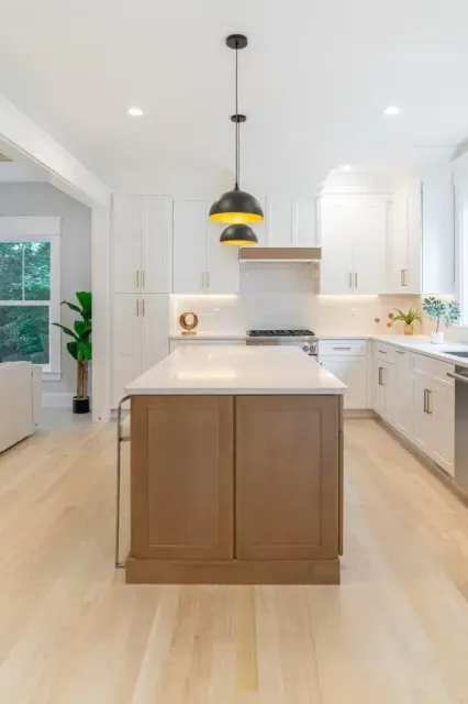 Bright modern kitchen with white cabinets, wood island, and pendant lights