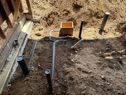 Underground PVC sewer and drain pipes installed in a residential foundation before concrete is poured.
