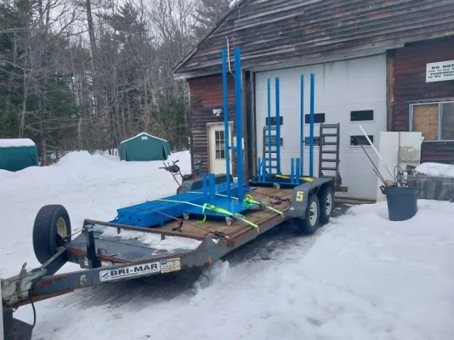 Trailer loaded with blue metal frames outside workshop, showcasing MIG and flux core welding service by Warrior Welding LLC in winter conditions