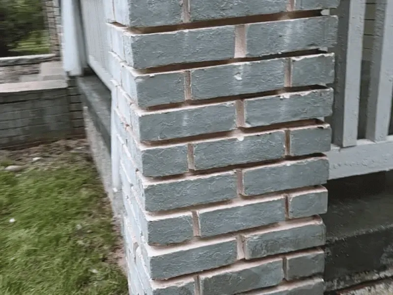 Mason repairing brick chimney crown and mortar joints