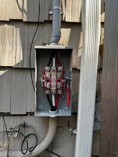 Electrical Panel with Red and Black Cables Connected, Installed on the Exterior Wall of a House