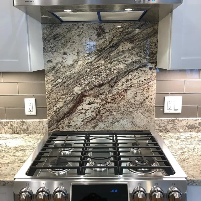 A stove top oven with a granite counter top behind it