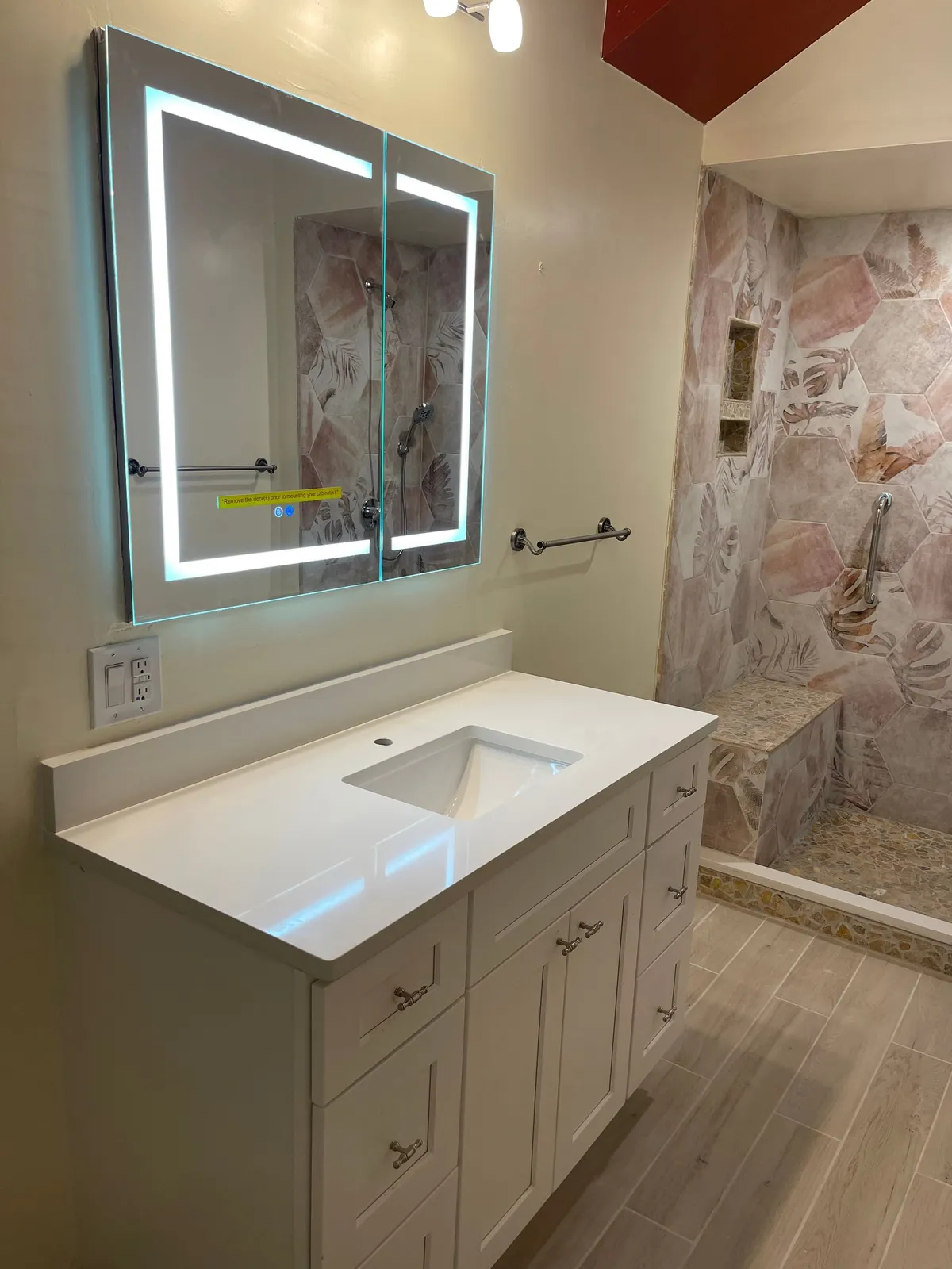 a bathroom with a sink and mirror in front of a shower