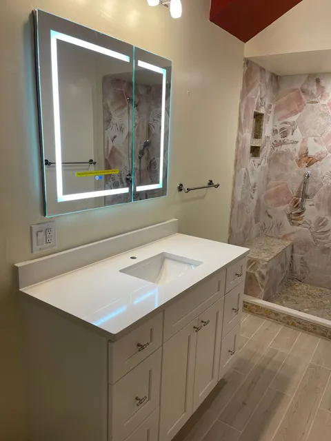 a bathroom with a sink and mirror in front of a shower