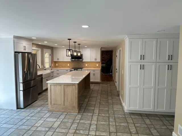 Modern kitchen with stainless steel appliances, white cabinets, tiled floor, and a large island