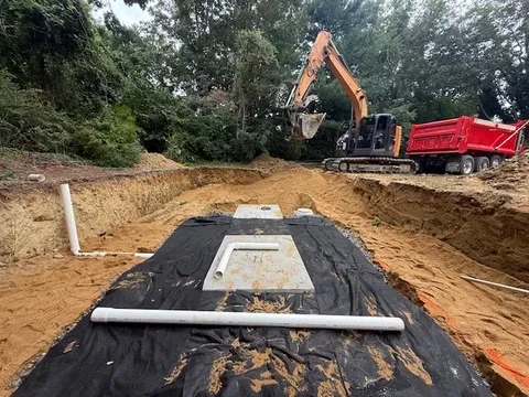 Excavator and red truck at an outdoor construction site.