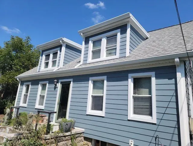 A blue house with white trim and a gray roof