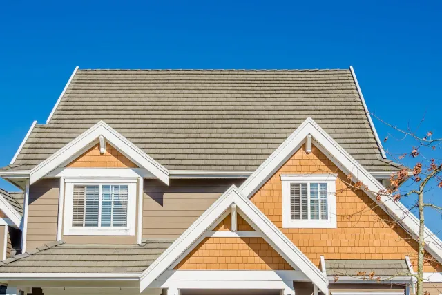 Tan and orange house with white trim, blue sky background.