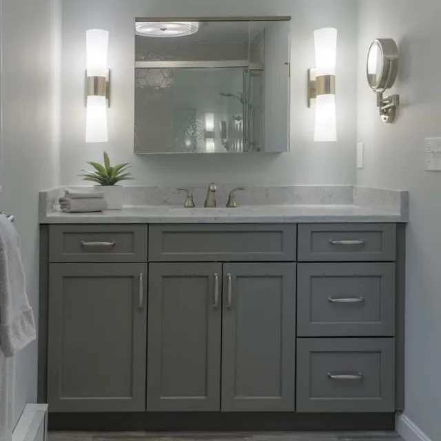 A contemporary bathroom showcasing gray cabinets and a sleek mirror.