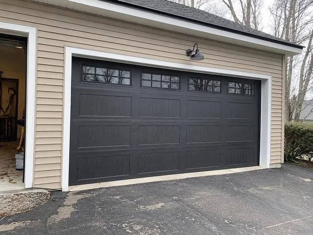 Modern New England home with a new dark bronze double residential garage door installed by Nolin Overhead Doors