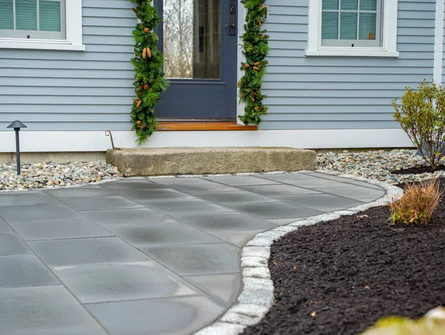 Front door with garland and stone walkway