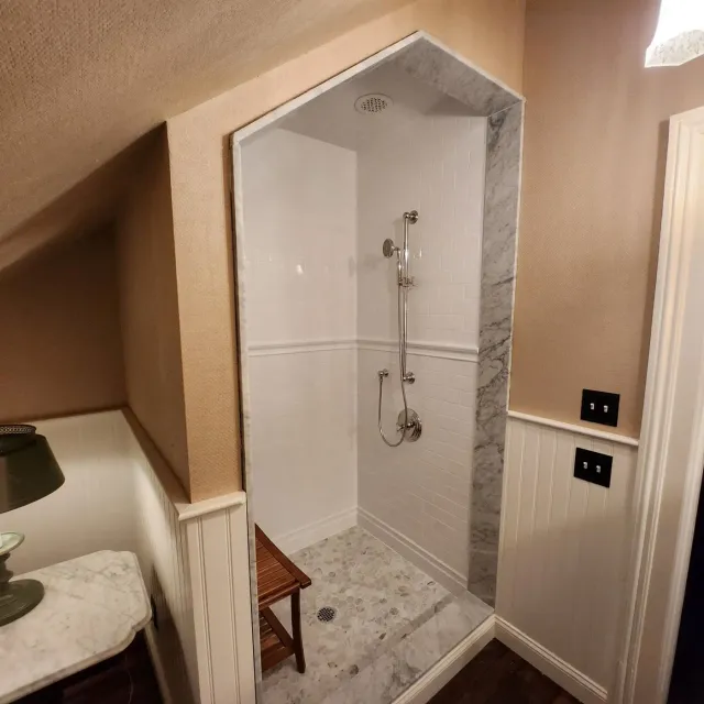 Walk-in shower with subway tile, a marble surround and a hex mosaic floor