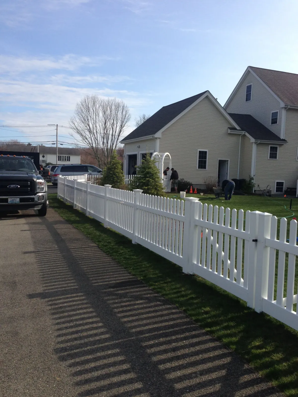 A white picket fence is in front of a house.