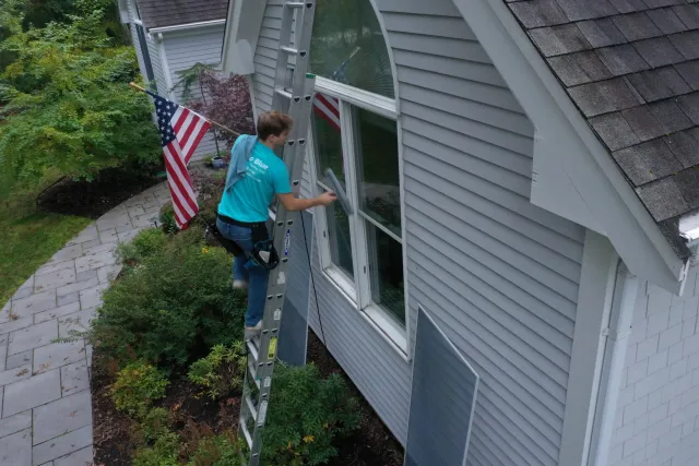 Person on ladder cleaning windows with American flags