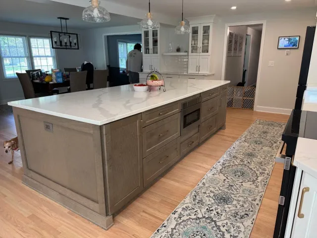 large kitchen island with light brown cabinetry and marble countertop