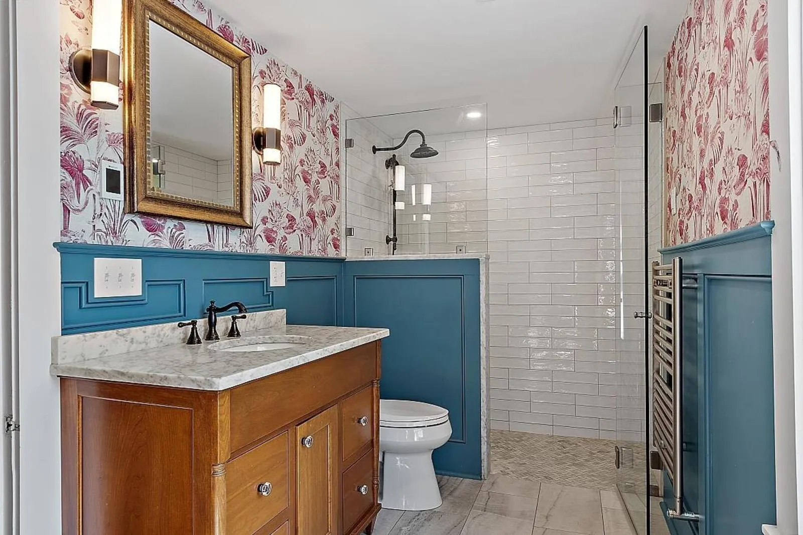 Rustic-style bathroom with wood-paneled accents and a glass-enclosed shower, designed by Oxland Builders in New Hampshire