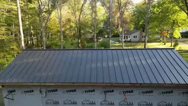 Partially finished roof with trees and a house in the background, seen from above