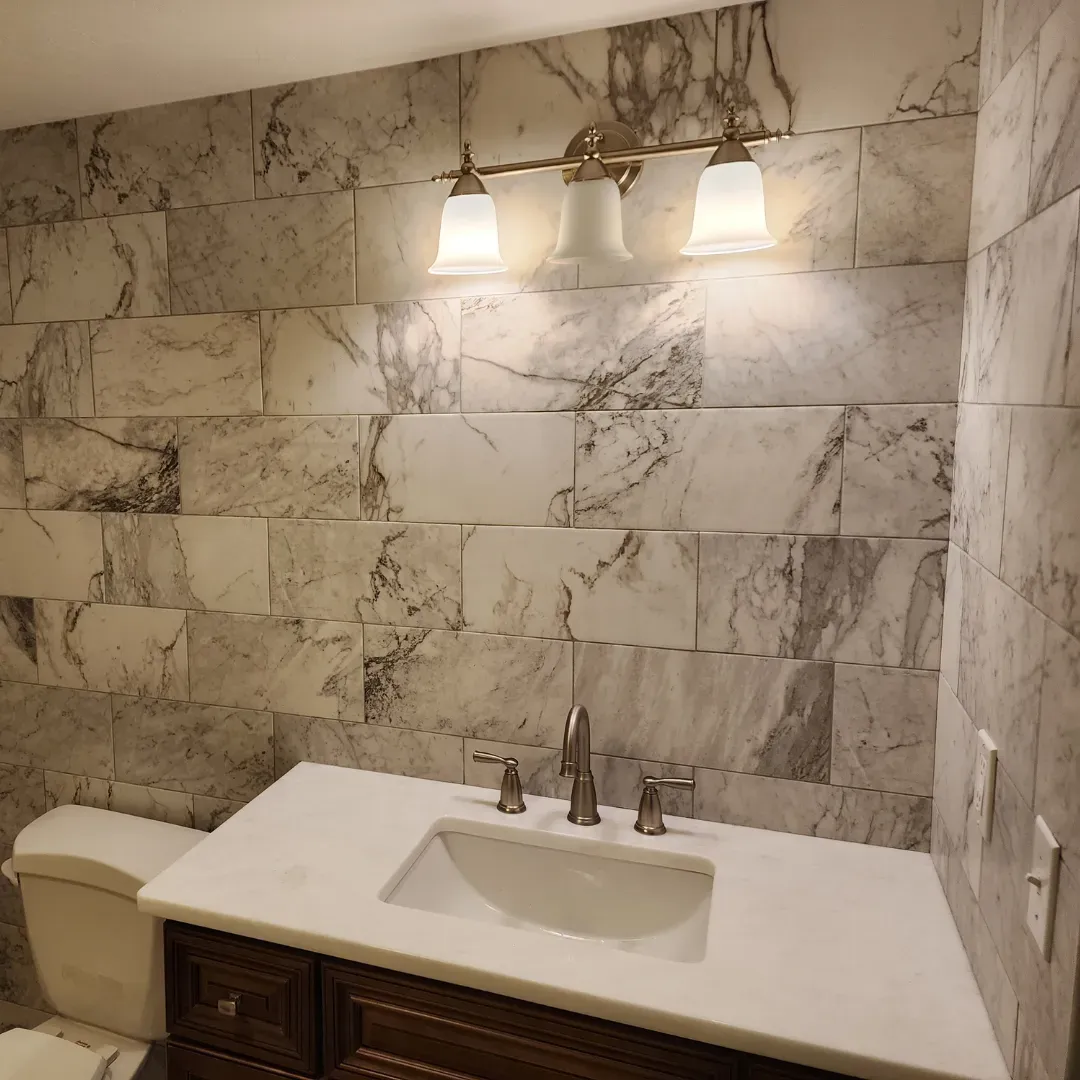 Master bath vanity with veined marble-look tile wall and quartz countertop by Link Services Pro in Shrewsbury, MA