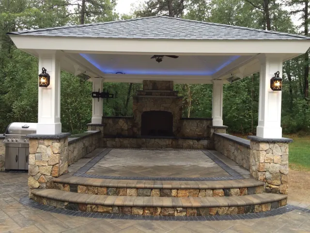 A gazebo with a fireplace in the middle of it