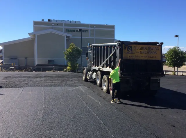 a dump truck is being loaded with asphalt in a parking lot