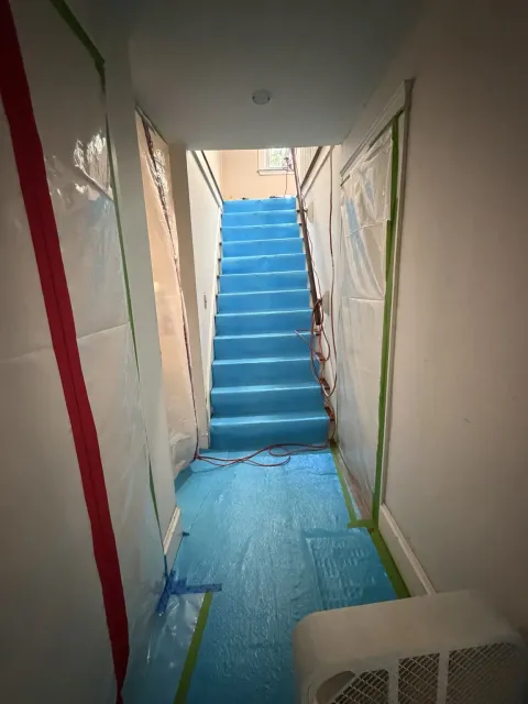 Protective floor covering and plastic sheeting installed along the interior route to the attic work zone during Smithfield Rhode Island mold remediation project