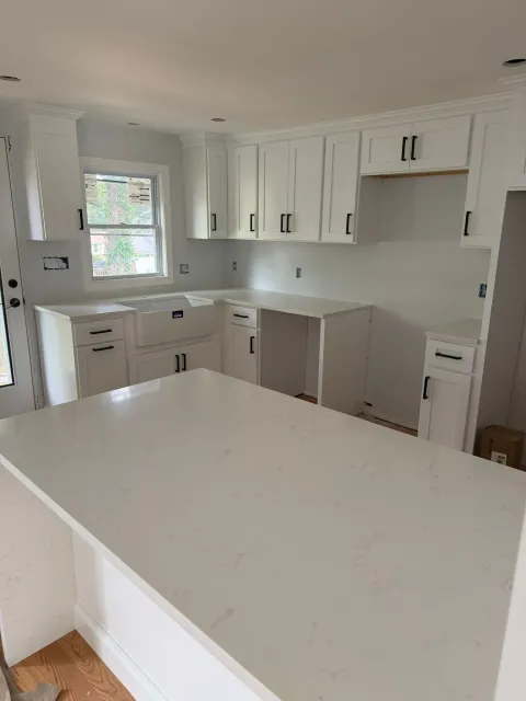Bright white kitchen with large island, shaker cabinets, and a window above the sink.