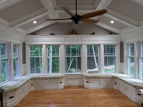 Bright sunroom with built-in window seats and ceiling fan