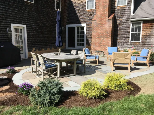 A patio with a table and chairs in front of a house