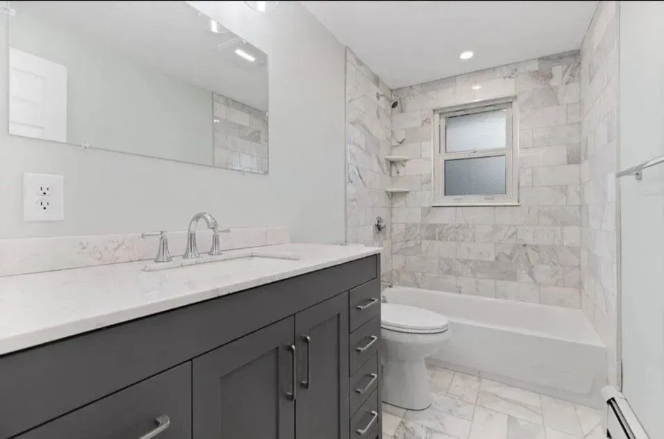 A bathroom with a sink, toilet, tub and mirror.