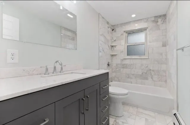 A bathroom with a sink, toilet, tub and mirror.