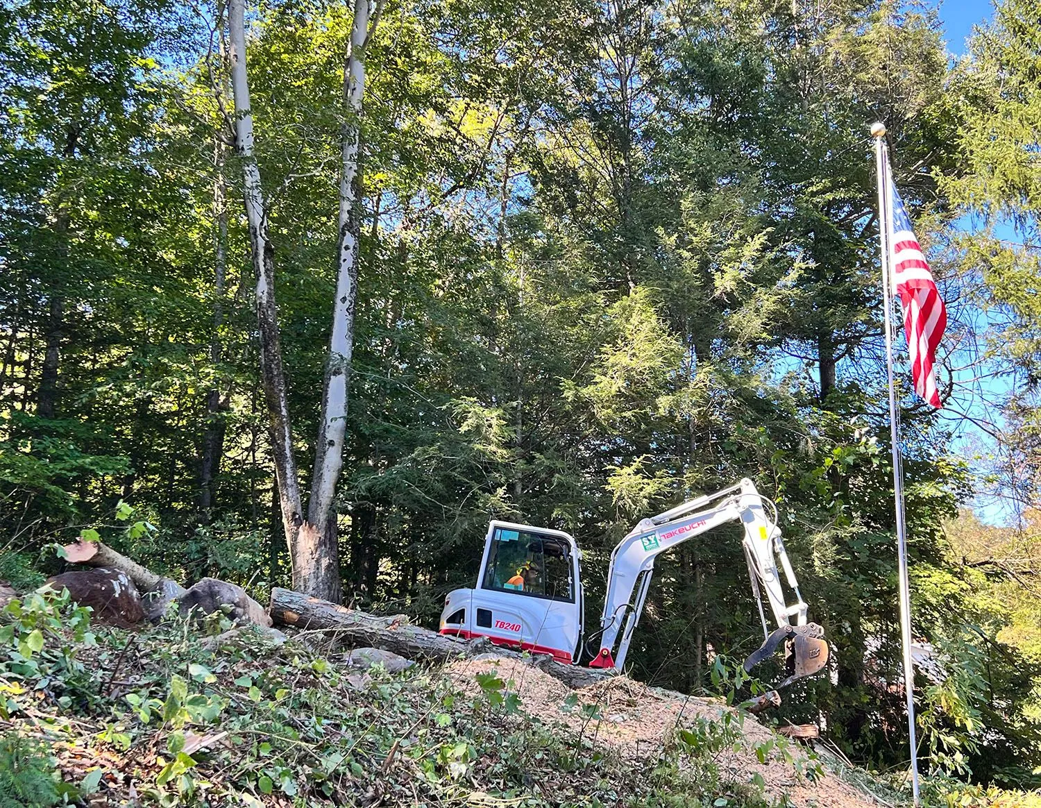 An excavator is sitting on top of a hill next to a flag